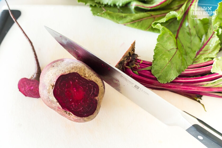 A raw beet with the stem and bottom cut off for roasting.