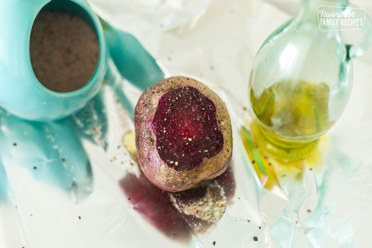 A raw beet covered in olive oil and sprinkled with salt and pepper