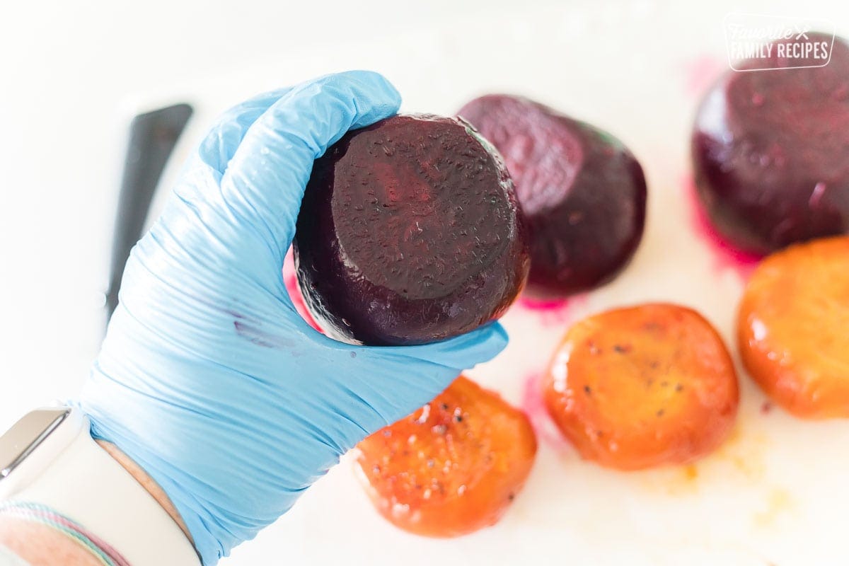 A photo of a beet with a gloved hand holding the beet. 