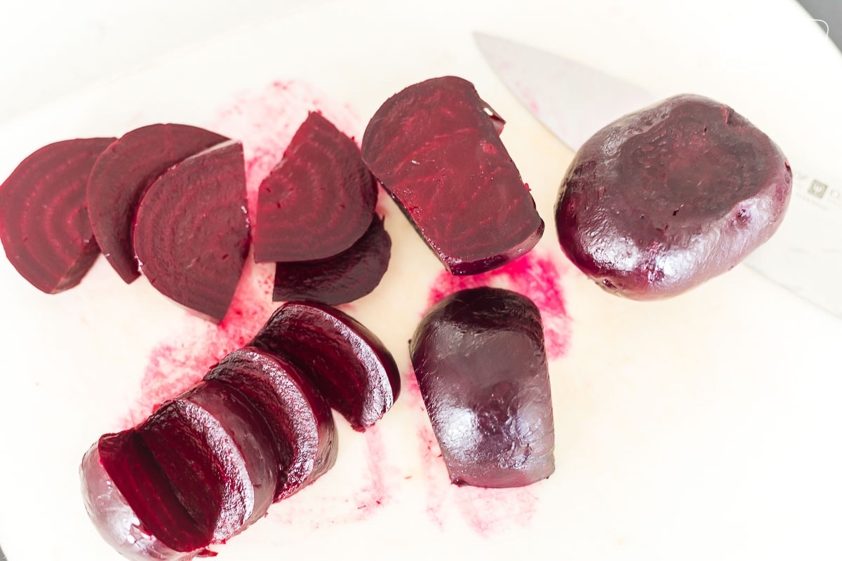 Beets sliced on a white cutting board.