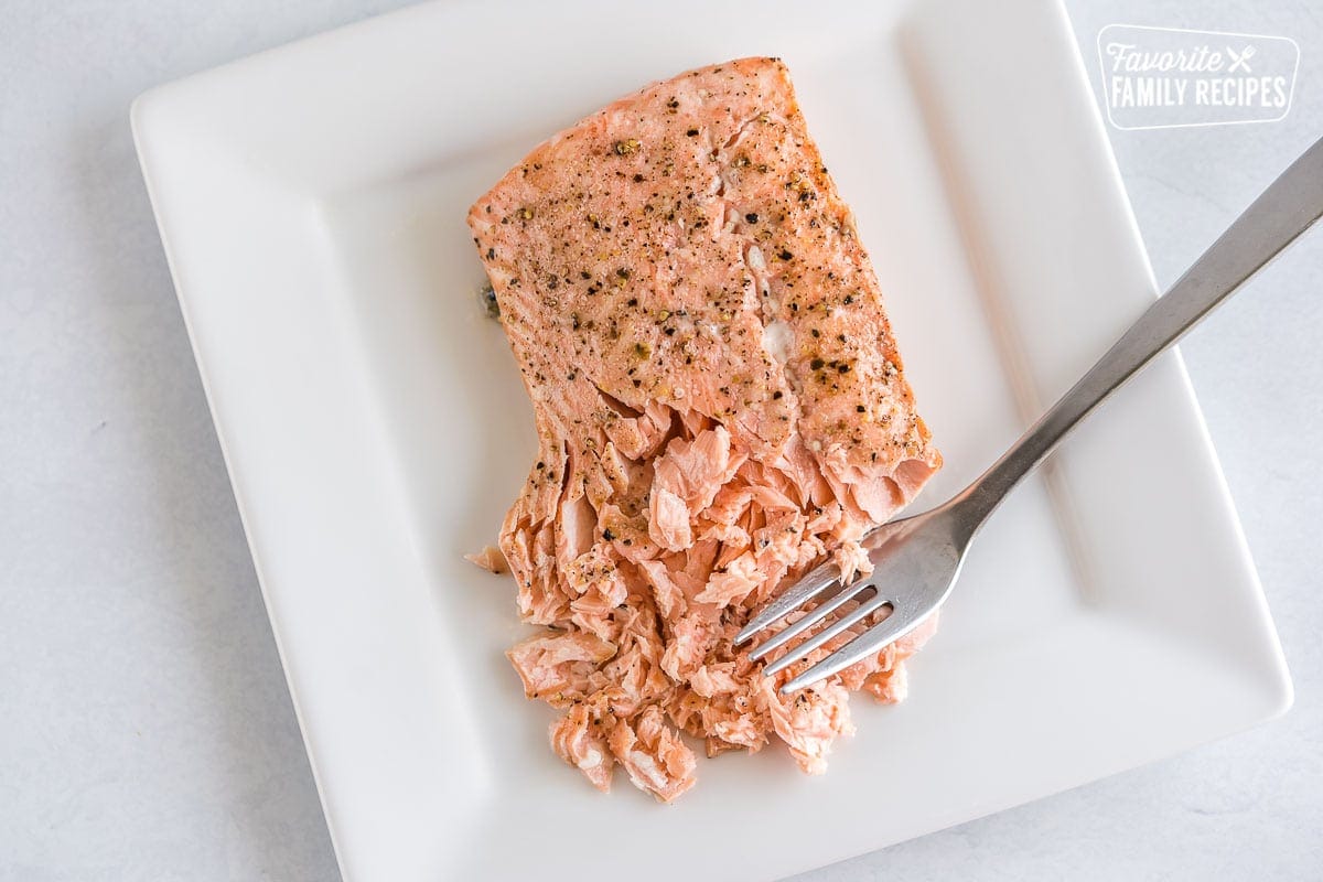 A salmon fillet being flaked with a fork