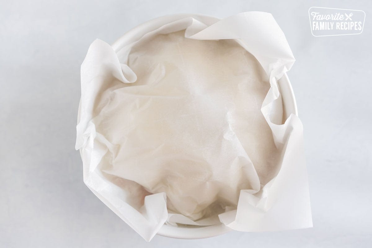 A bowl of salmon rice covered with a piece of parchment paper
