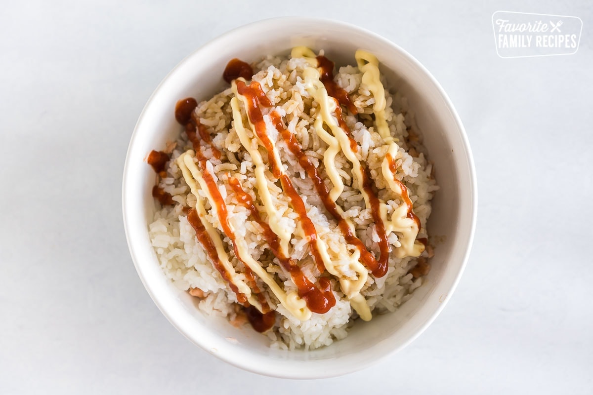 Salmon and rice in a bowl topped with soy sauce, sriracha, and kewpie mayo