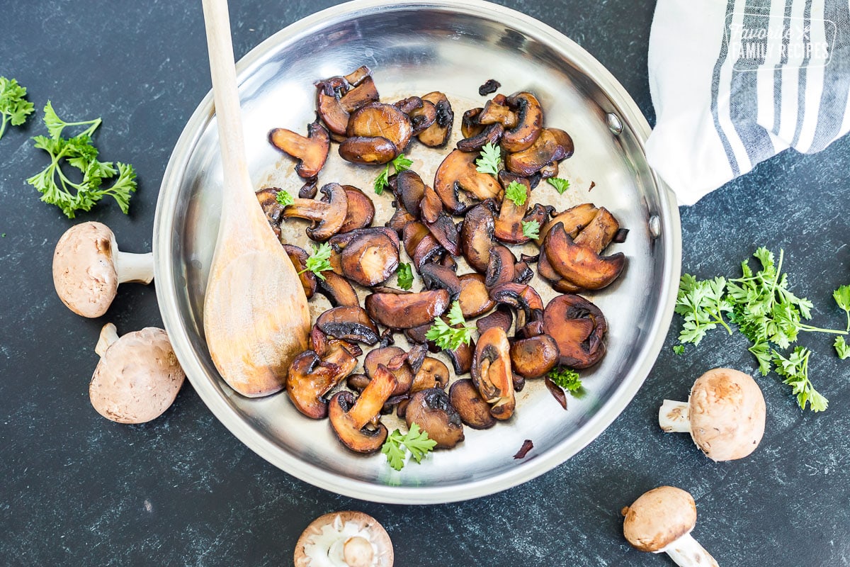 Sautéed mushrooms in a pan with a spatula and parsley