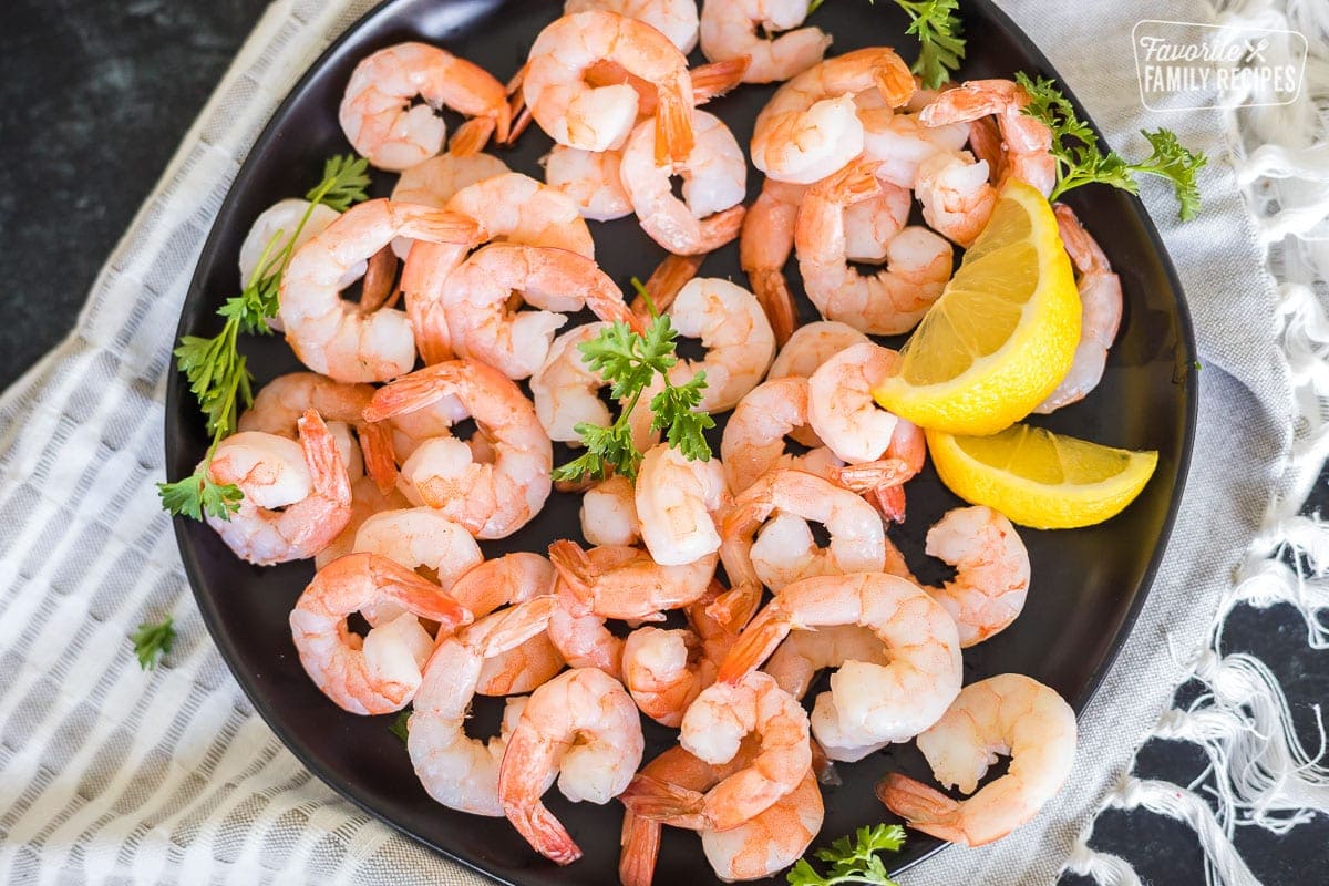A plate of prepared cocktail shrimp with lemons for garnish.