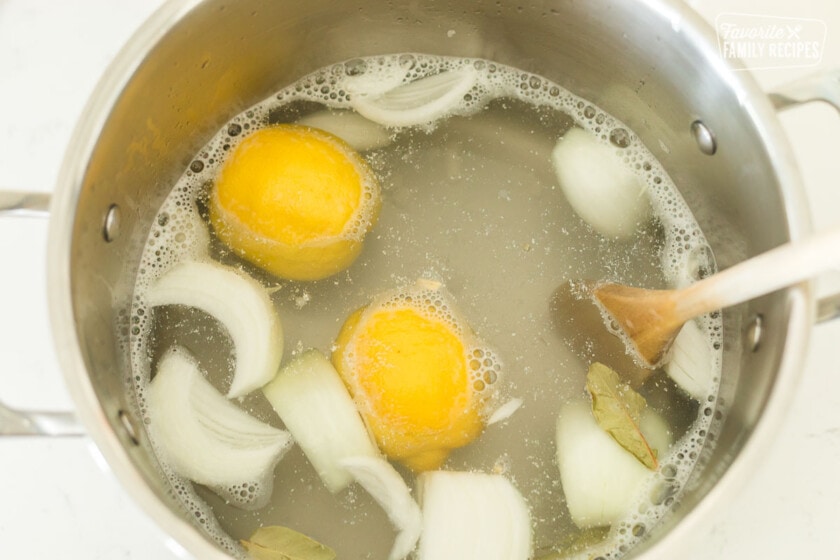 A pot with water, lemons, onion, and bay leaves