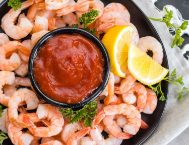 A top view of cocktail shrimp with a bowl of homemade cocktail sauce
