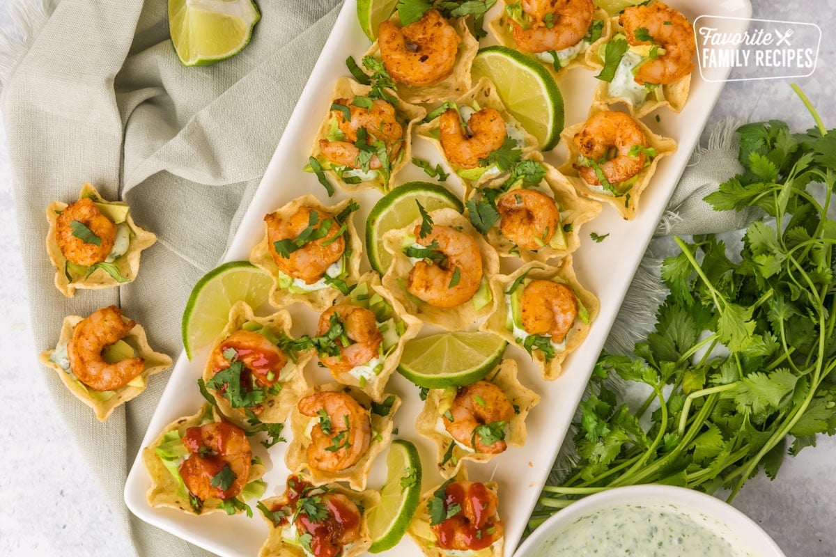 These shrimp taco bites with cilantro cream sauce are the perfect quick appetizer. Spicy and easy, these tasty little bites can be made in less than 15 minutes! Plated shrimp taco bites with limes and cilantro