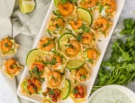 Plated shrimp taco bites with limes, avocado, cilantro sauce and cilantro
