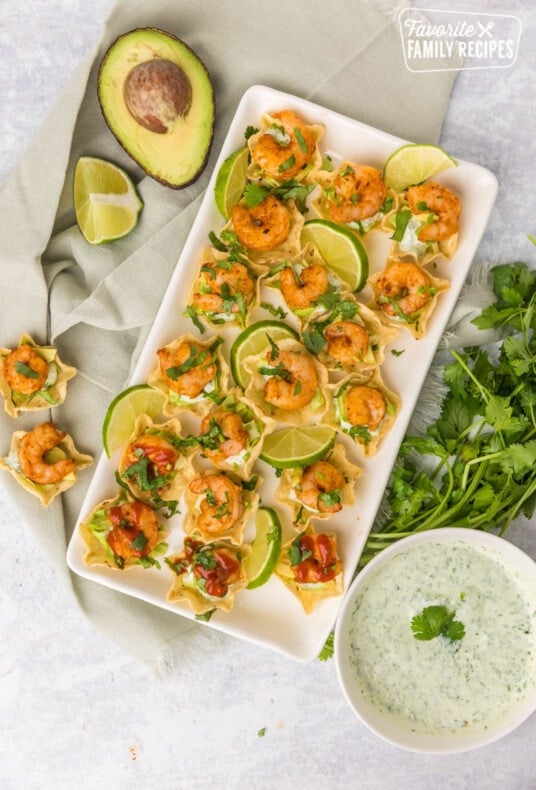 Plated shrimp taco bites with limes, avocado, cilantro sauce and cilantro