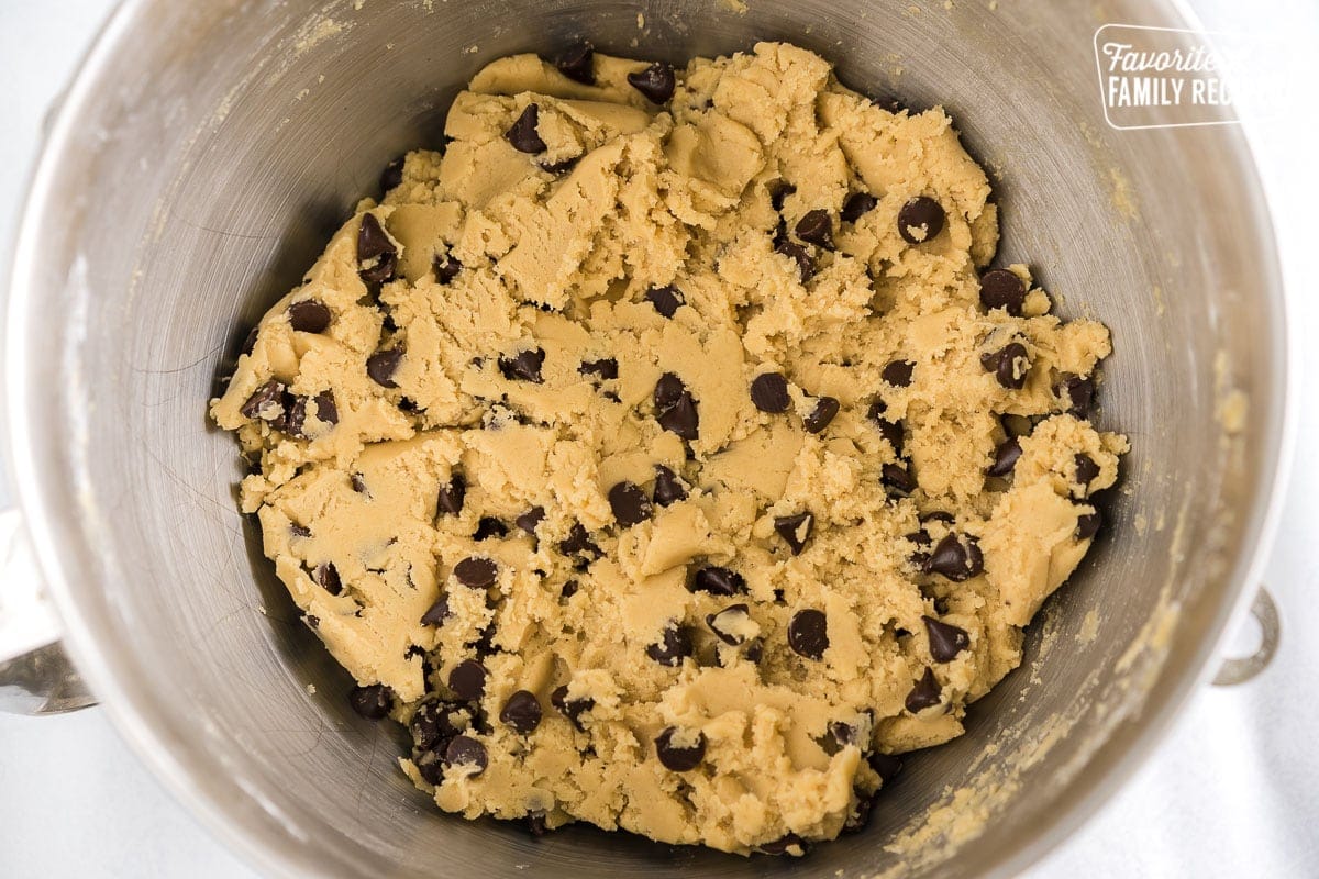 a silver mixing bowl full of chocolate chip cookie dough