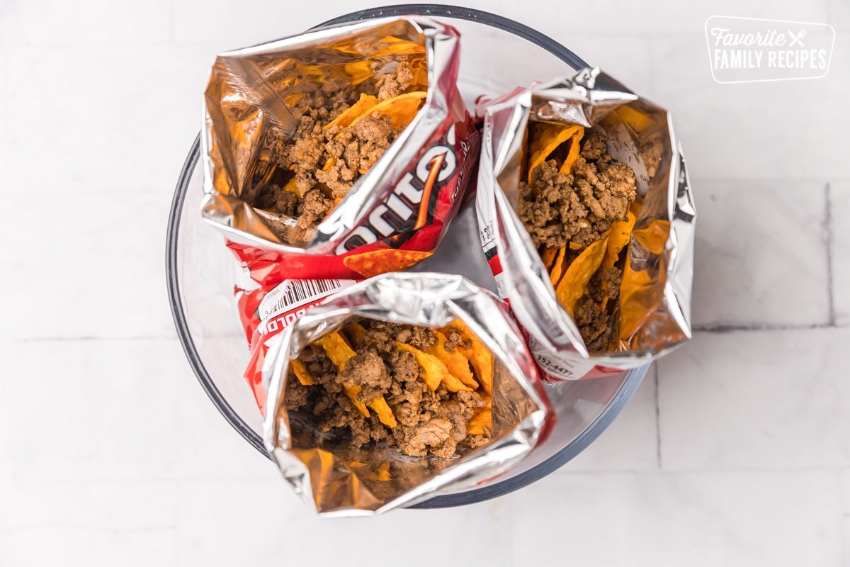 Three open bags of Doritos with meat inside