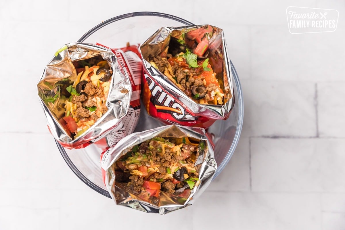 Three open bags of Doritos with toppings and meat inside