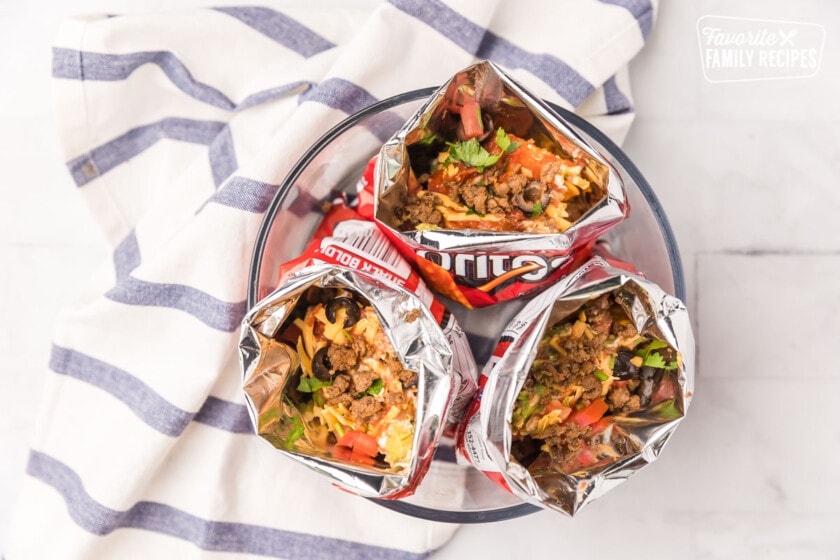 Three open bags of Doritos with toppings and meat inside