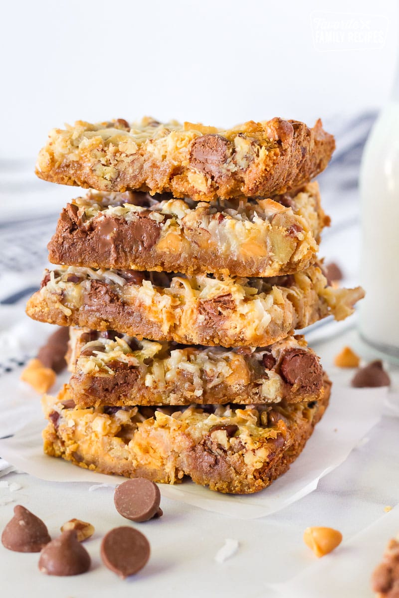 These 7 Layer Bars are always a hit! The coconut, milk chocolate chips, and pecans caramelize while it bakes. A quick and easy delicious dessert. Tall stack of 7 Layer Magic Cookie Bars.