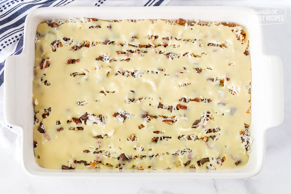 Sweetened condensed milk poured on top of 7 Layer Magic Cookie Bars.