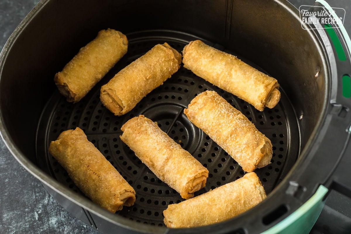 Frozen air fryer egg rolls in an air fryer basket, uncooked