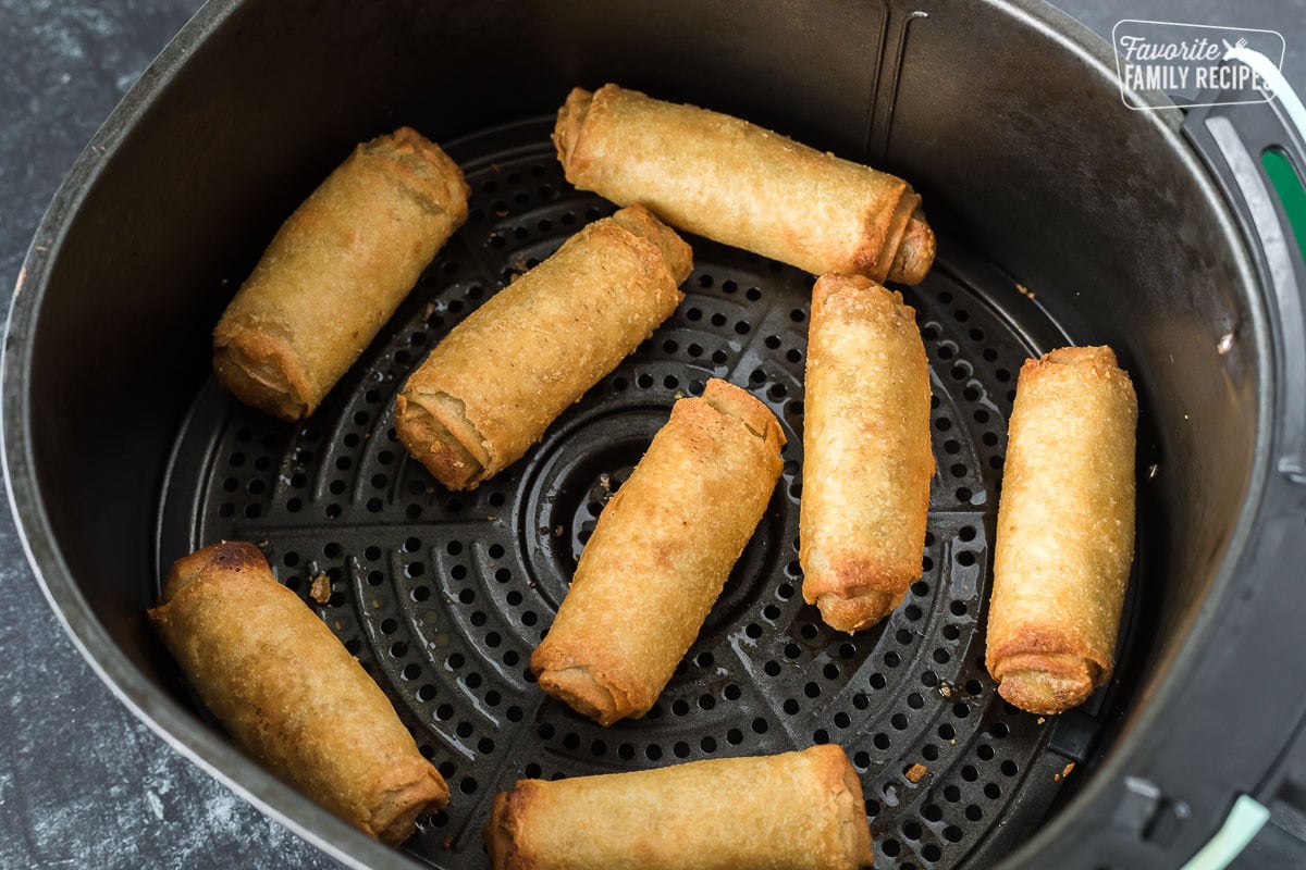 Frozen air fryer egg rolls that have been cooked in an air fryer basket.