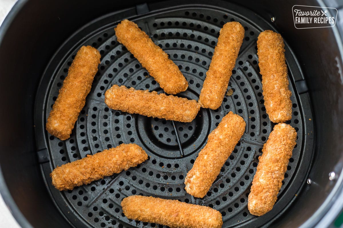 Uncooked frozen mozzarella sticks in an air fryer basket