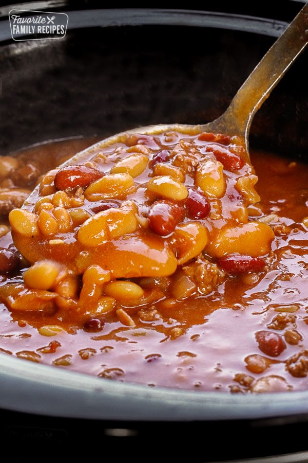BBQ Beans in a Crock Pot being scooped with a serving spoon