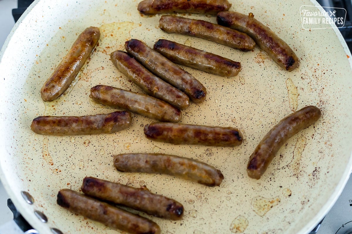 Link sausages cooking in a large skillet