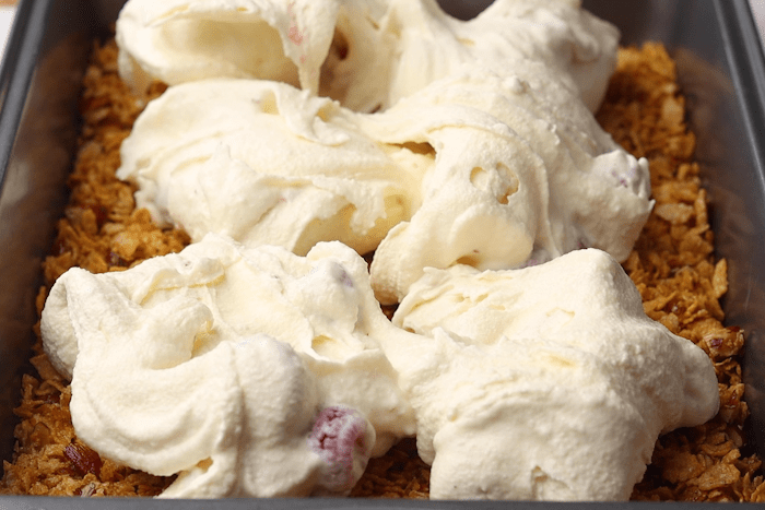 Cereal mixture and raspberry ice cream mix in a 9x13 metal pan for Raspberry Fried Ice Cream.