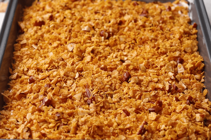 Cereal mixture lightly pressed over ice cream in a metal pan for Raspberry Fried Ice Cream.