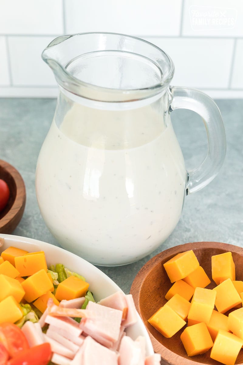 A clear salad dressing pitcher with homemade Ranch dressing
