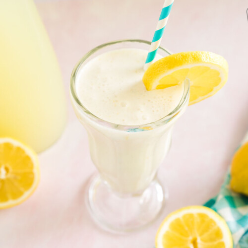 Chick Fil A Frozen Lemonade in a tall glass garnished with a lemon slice and a blue striped straw