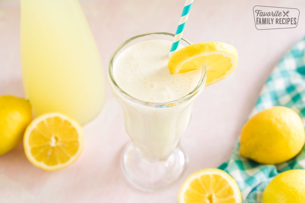 Chick Fil A frosted Lemonade in a tall glass garnished with a lemon slice and a blue striped straw.