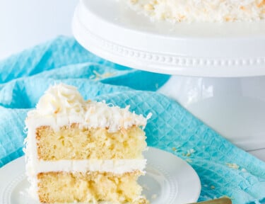 Plate of sliced coconut cream cake with coconut frosting.