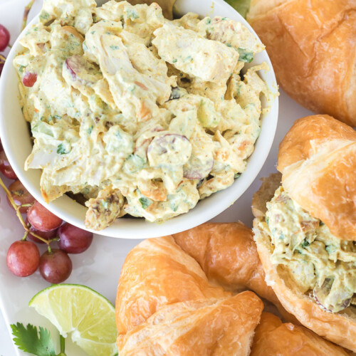 Curry chicken salad in a bowl next to croissants