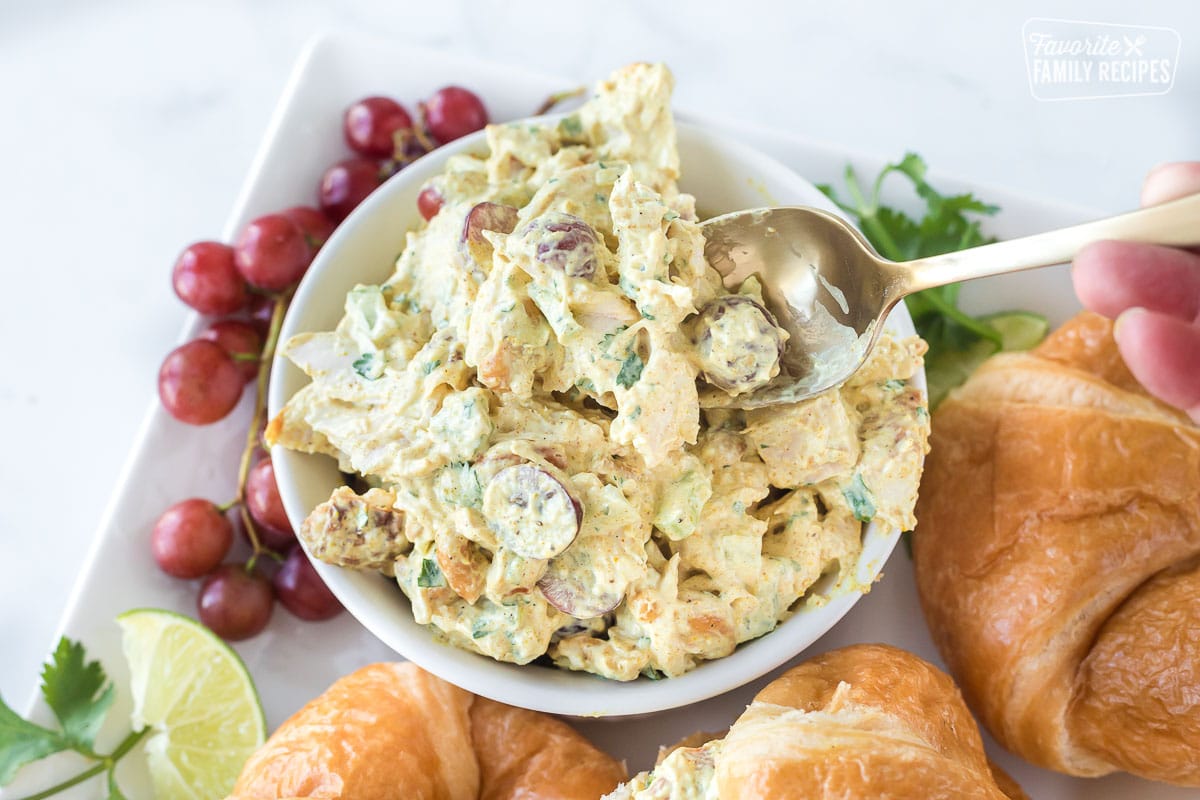 Curry chicken salad in a small bowl with a spoon.