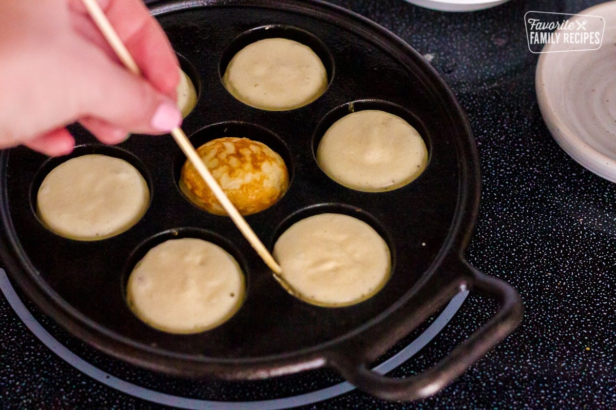 Danish Aebleskiver being flipped in pan.