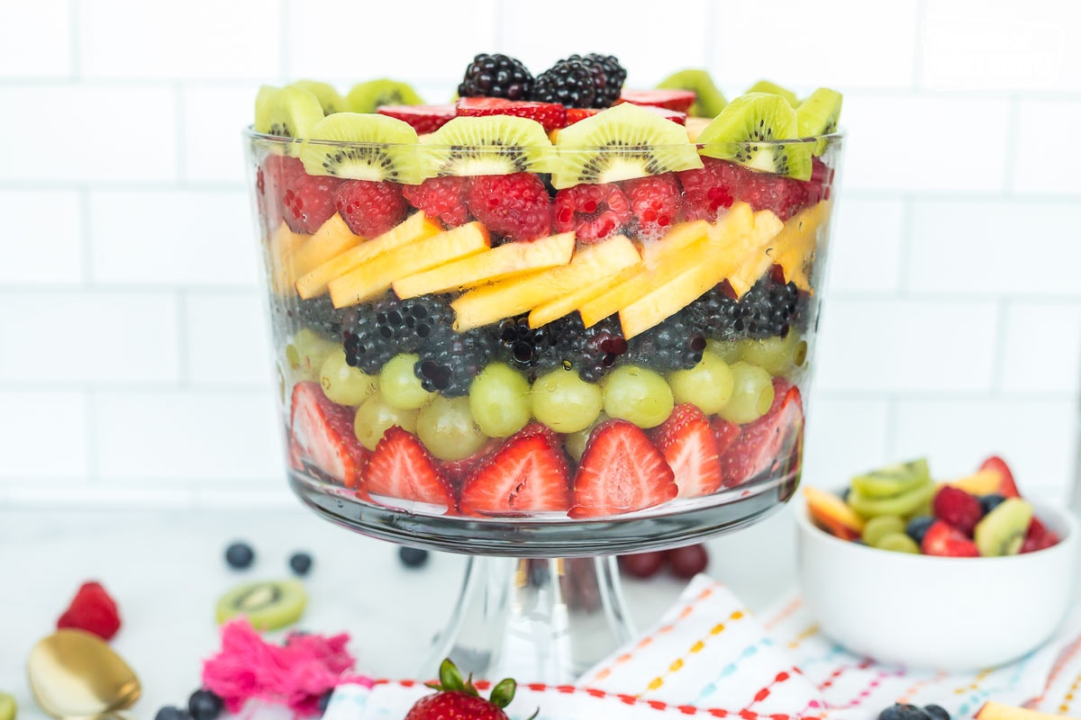 A trifle dish layered with strawberries, grapes, blackberries, nectarines, raspberries, and kiwi