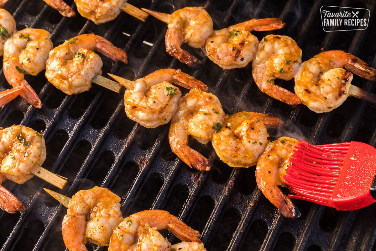 Grilled shrimp marinade being brushed on shrimp skewers on the grill
