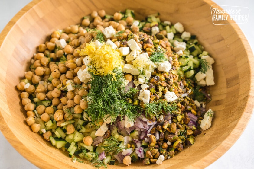 A large wooden bowl full of orzo salad ingredients