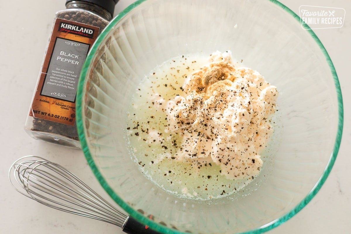 Ingredients to make peppercorn sauce in a bowl including mayonnaise, cracked peppercorns, and lemon juice