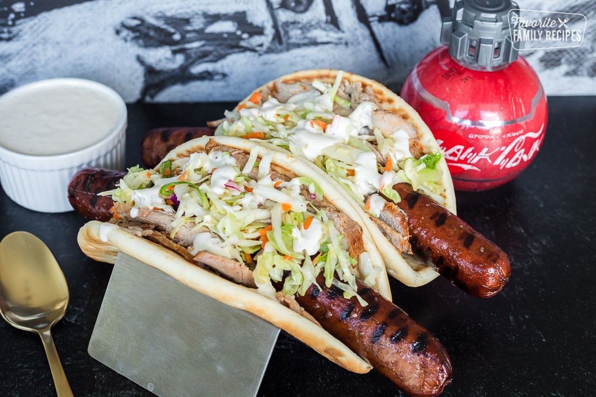 Two Ronto Wraps topped with slaw and next to a bowl of peppercorn dressing