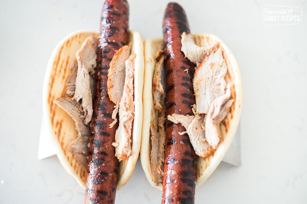 Two pita breads with sliced pork and smoked sausage