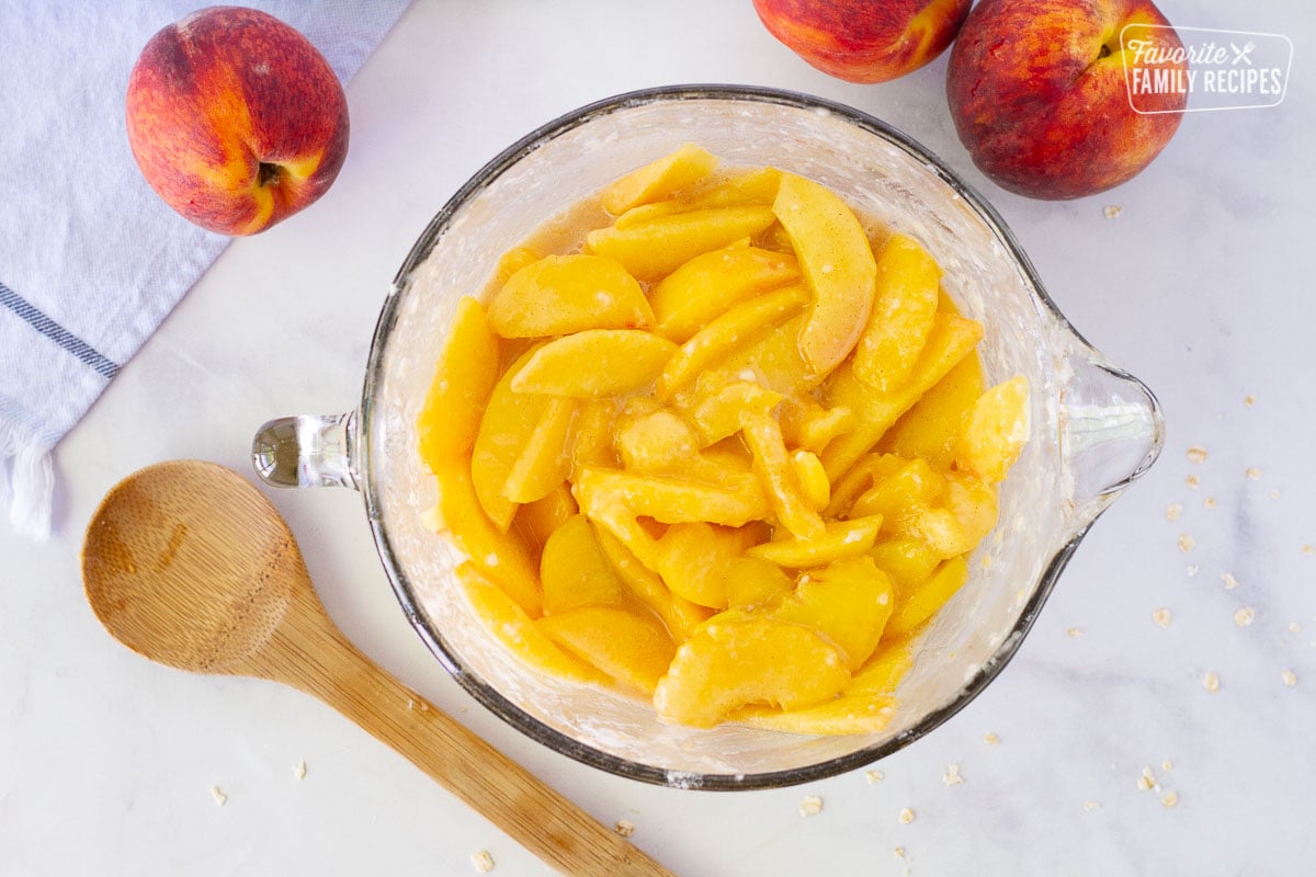 Fresh sliced peaches in a mixing bowl for Summer Peach Crisp filling.