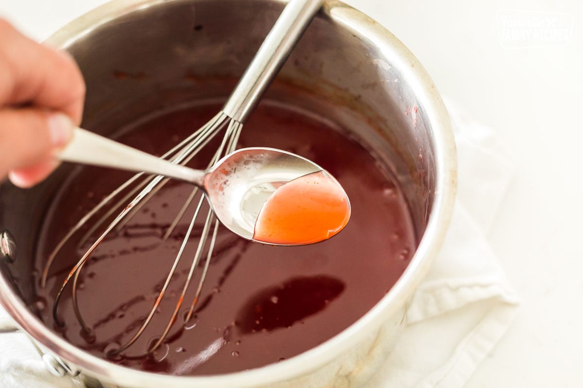 Sweet and sour sauce coating a silver spoon.