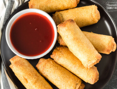 Egg rolls on a plate with a bowl of sweet and sour sauce