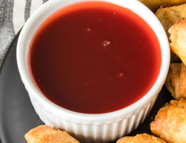 A close up of a serving bowl of sweet and sour sauce
