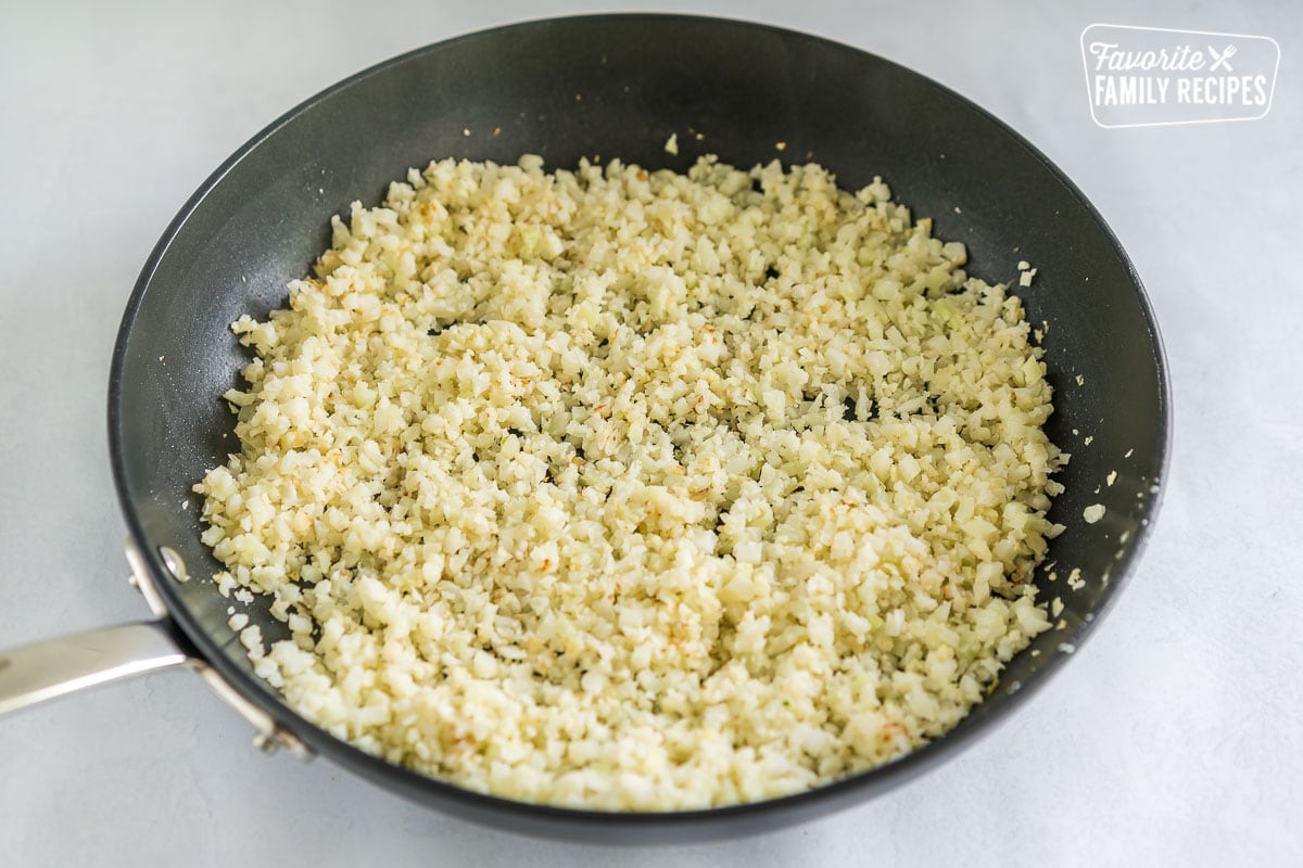 Riced cauliflower being cooked in a skillet