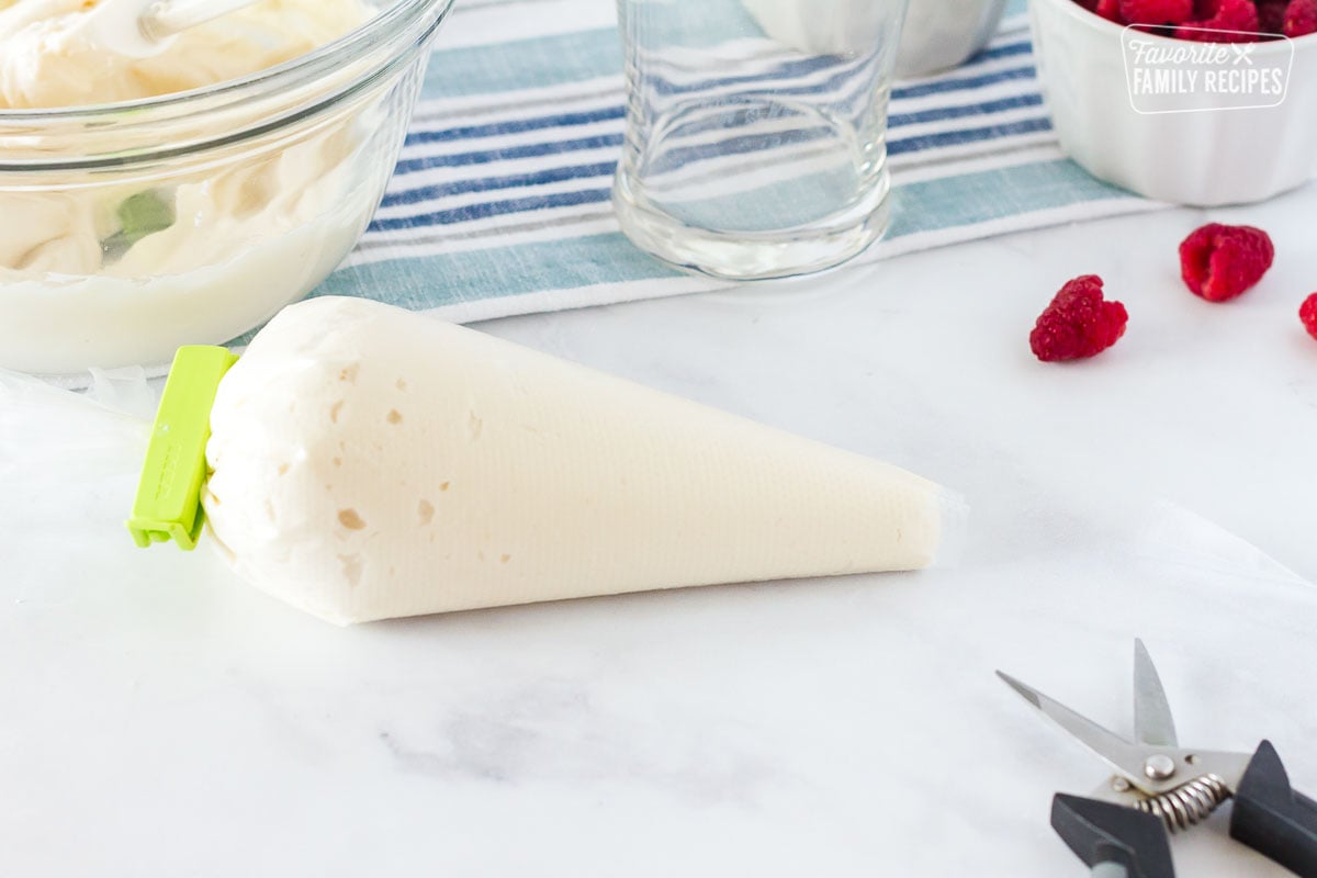 Piping bag cut with scissors to frost White Chocolate Raspberry Cake.