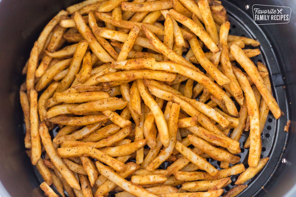 Cooked French fries in an air fryer basket.