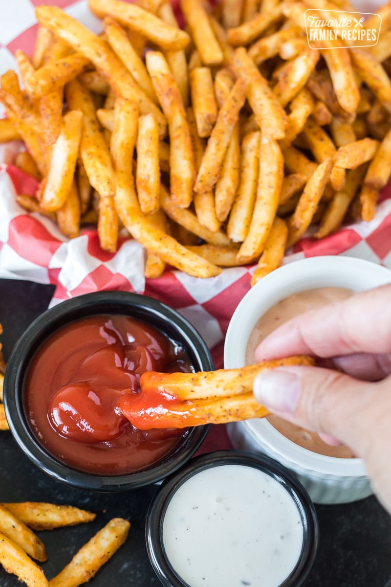 Air fryer fries being dipped in ketchup.