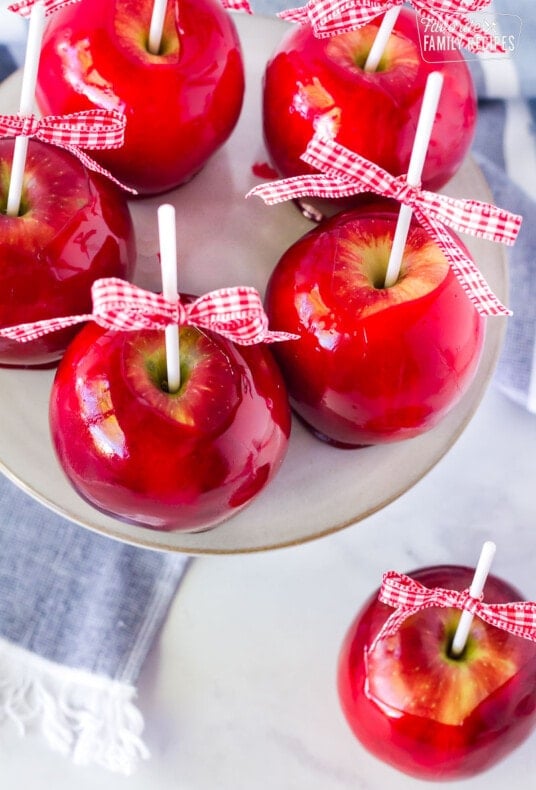 Bright red homemade candy apples with shiny, crunchy candy shells, perfect for Halloween and fall treats.