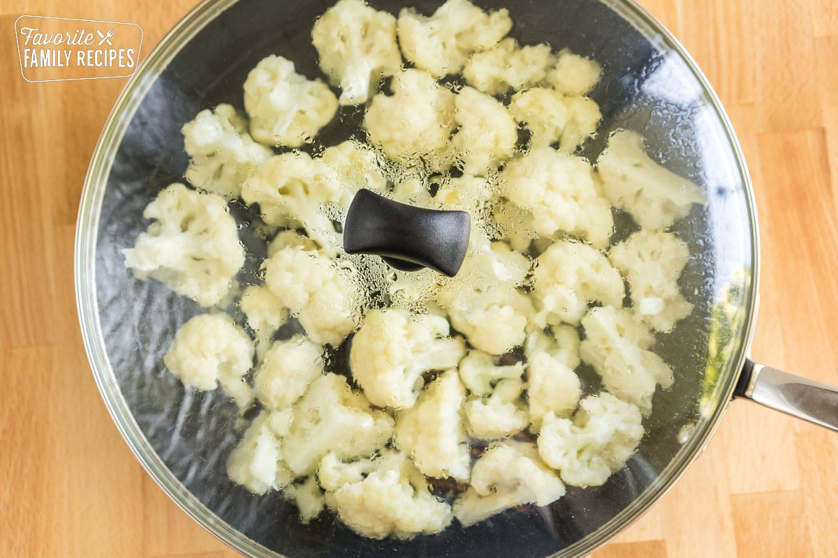 Cauliflower florets steaming in a skillet